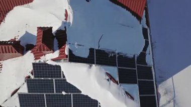 Kışın şiddetli bir kar yağışı sonrasında evin çatısındaki güneş panellerinin hava görüntüsü. Yenilenebilir enerji üretim modülleri