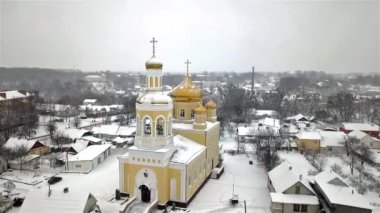 Kışın, Ukrayna 'nın küçük bir kasabasında kar yağışı sırasında bir kilisenin havadan görünüşü