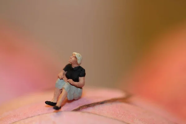 Figurilla Miniatura Una Mujer Solitaria Sentada Sobre Fondo Rosa Abstracto —  Fotos de Stock