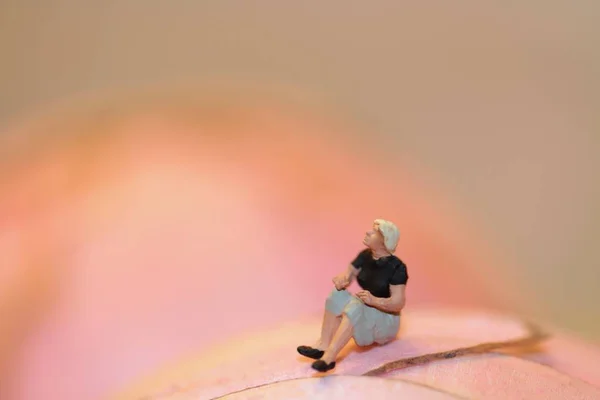 Миниатюрная Фигурка Одинокой Женщины Сидящей Абстрактном Розовом Фоне — стоковое фото