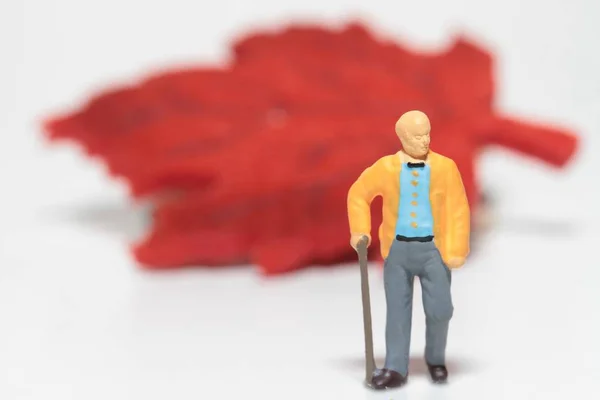 Miniatura Homem Velho Com Uma Folha Outono Vermelho Fundo — Fotografia de Stock