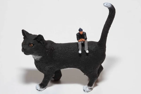 巨大な黒猫の上に立っている人々のミニチュア — ストック写真