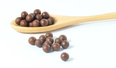 Tahta kaşık Bitkisel öksürük pastilleri beyaz bir arka plan üzerinde dolu