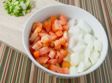 Doğranmış domates, soğan ve taze soğan kesme tahtası üzerinde