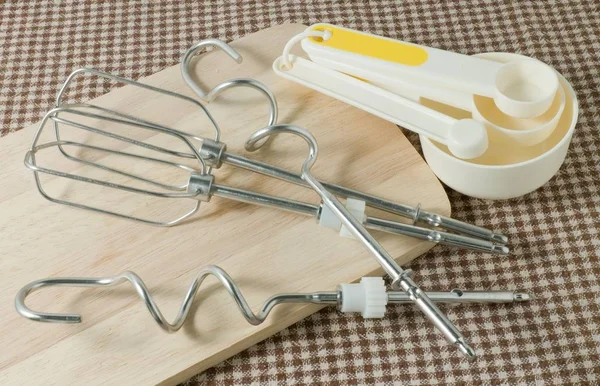 Cucharas de medición y batidor de metal en tablero de madera — Foto de Stock