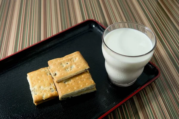 Biscoito com um copo de leite na placa — Fotografia de Stock