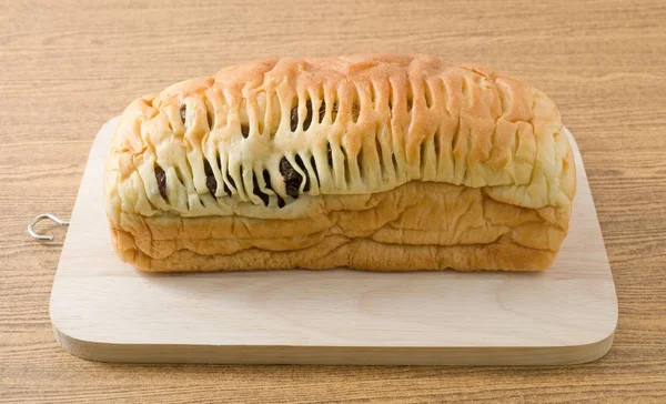 Bochenek chleba rodzynkowego na drewnianą deską do krojenia — Zdjęcie stockowe