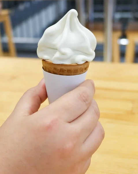Mão segurando baunilha cone de gelado macio — Fotografia de Stock