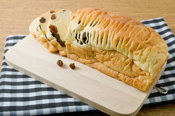 Delizioso pane all'uvetta sul tagliere di legno — Foto Stock