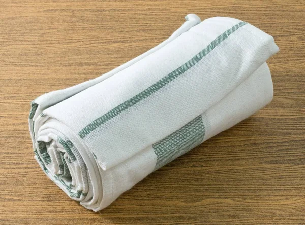 Белый и зеленый кухонный полотенце на деревянный стол — стоковое фото