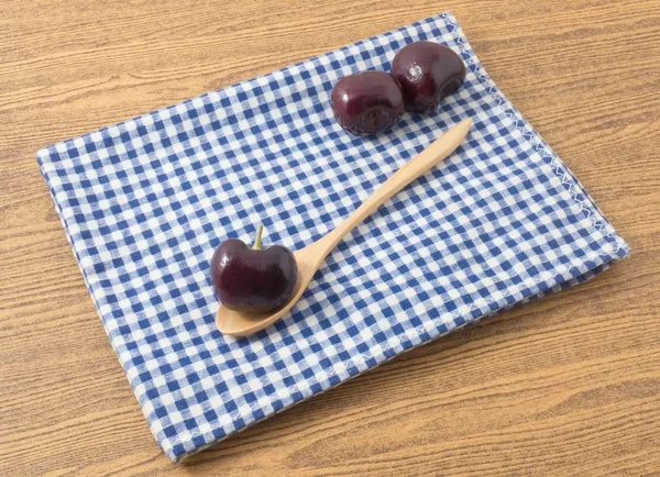 Três ameixas vermelhas no guardanapo verificado azul — Fotografia de Stock
