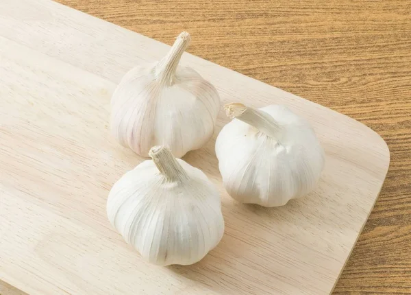 Tre lampadine di aglio sul tagliere di legno — Foto Stock