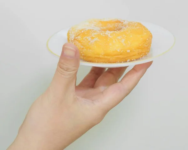 Hand hält ein Gericht Donut mit Zucker — Stockfoto