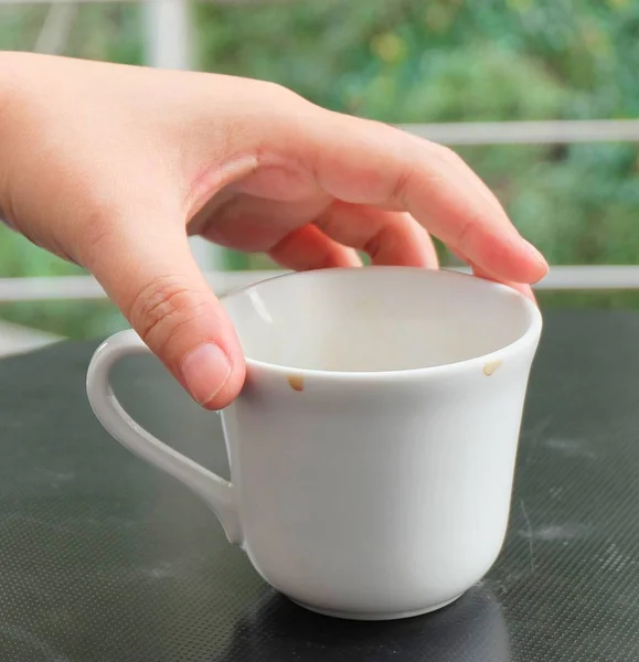 Mão segurando vazio xícara de café na mesa — Fotografia de Stock