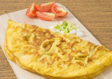 Domates ve yeşil soğan kesme tahtası üzerinde Tay omlet