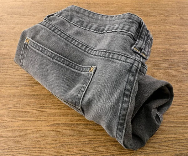 Close Up of Black Denim Jean on Wooden Table — Stock Photo, Image