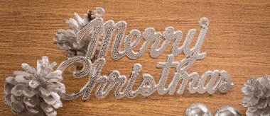 Noel süsler, Merry Christmas metin Baubles ve Pinecones ahşap masa, tarih ile imzalayın Noel kutlamaları için.