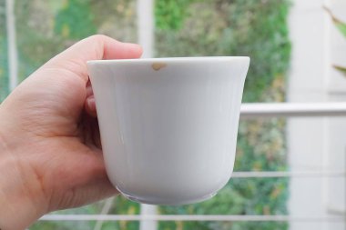 Mutfak ve gıda, masada Kahve içtikten sonra boş bir bardak tutan el.