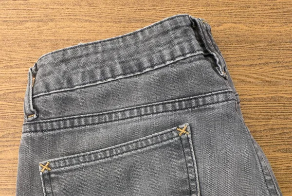 Close Up of Black Denim Jean on Wooden Table — Stock Photo, Image