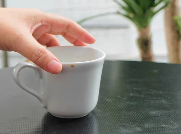 Mão segurando vazio xícara de café na mesa — Fotografia de Stock