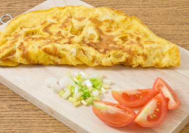 Tayland Mutfağı ve yemek, lezzetli Tay tarzı omlet bir kesme tahtası üzerinde kıyılmış yeşil soğan ve domates ile.