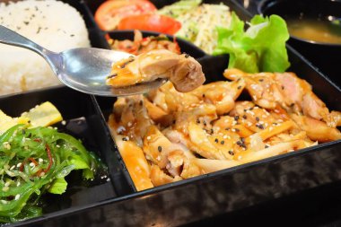 Geleneksel Japonya mutfağı, gümüş kaşıkla Teriyaki tavuk pilav, salata, Tamagoyaki veya haddelenmiş omlet, Hiyashi Wakame veya yosun salata ve Kimchi Bento kutusunda. 