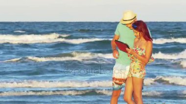 Genç bir çift deniz kenarında bir tablet ile bir yaz gününde eğleniyor