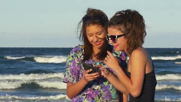 Adolescentes emocionados al mirar un teléfono inteligente en la playa — Vídeos de Stock