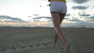 Kumsalda güneş doğarken koşan kız