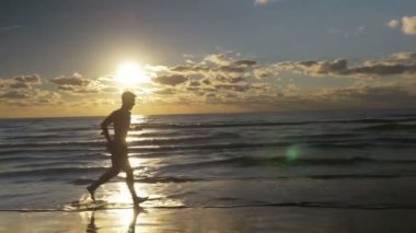Adam sahilde güneş doğarken Barefoot Koşu