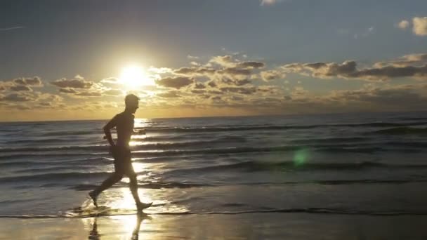 Homme jogging pieds nus sur la plage au lever du soleil — Video