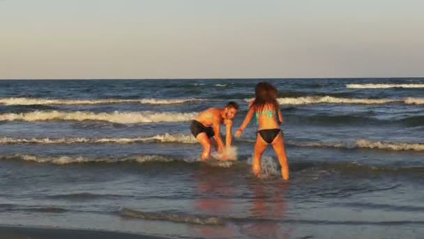 Hermosa pareja joven romántica burlándose unos a otros y jugando en el mar — Vídeos de Stock