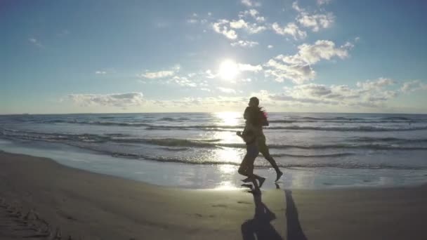 Par löpning och Kyssar på stranden vid havet — Stockvideo