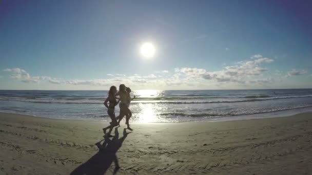 Tres amigas corriendo durante el entrenamiento en la playa a lo largo del mar — Vídeos de Stock