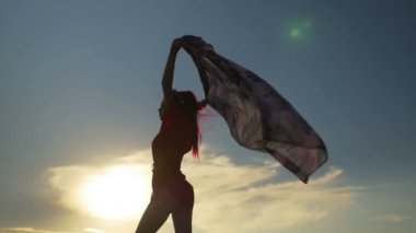 Dans ve sahilde bir eşarp tutan seksi kadın