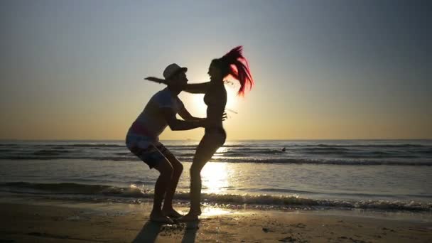 Jonge vrouw haar vriendje knuffelen en zoenen hartstochtelijk in slowmotion op het strand — Stockvideo