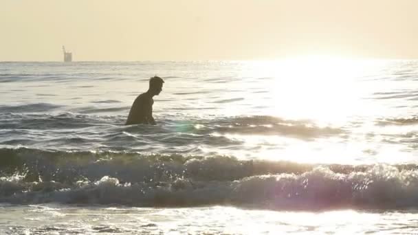 Genç adam denizde suya gidiyor ve ağır çekimde atlama — Stok video