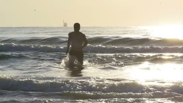 Man loopt uit zeewater in slow motion in schemerlicht — Stockvideo