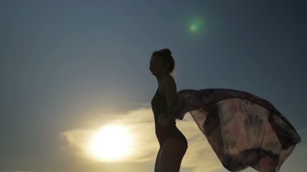Leende kvinna dansar med en halsduk i baddräkt i slow motion — Stockvideo