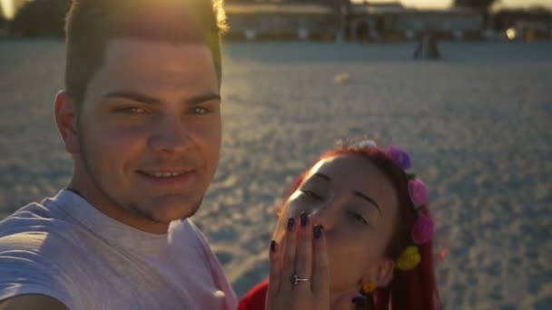 Hermosos amantes en vídeo llamando a sus amigos de la playa al atardecer — Vídeo de stock
