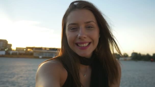 Удивлённая женщина на видео-вызове на пляже на закате — стоковое видео