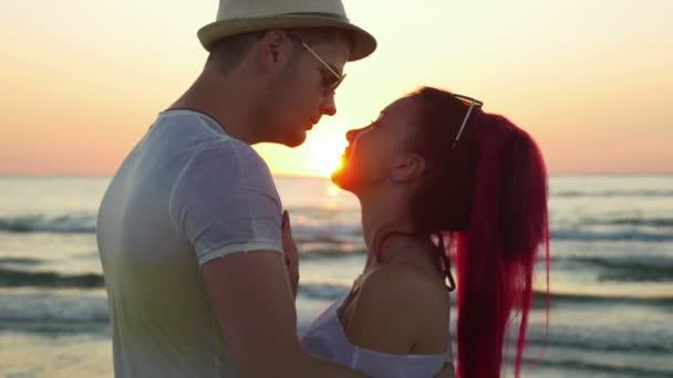 Young beautiful couple kissing at sunrise on the beach — Stock Video