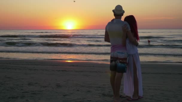 Пара обниманий и поцелуев на берегу песчаного пляжа на закате — стоковое видео