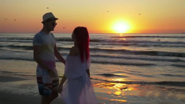 Pareja de hombres y mujeres jóvenes reunidos en una playa de arena y besándose con pasión al amanecer — Vídeos de Stock