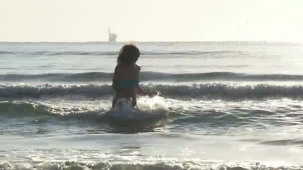 Ung kvinna kör i vågor i havet mot stranden — Stockvideo