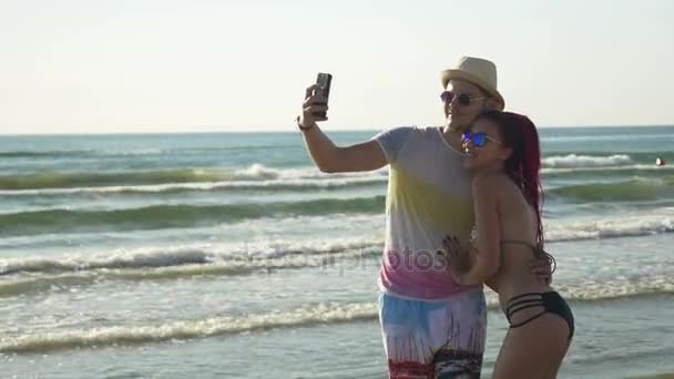 Счастливая молодая пара делает селфи на пляже — стоковое видео