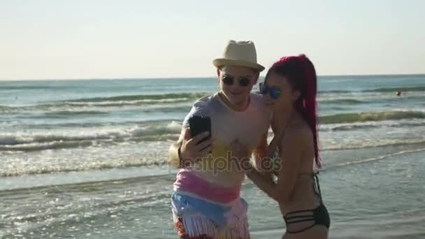 Hermosos amantes tomando selfie en la playa y mirando fotos — Vídeo de stock