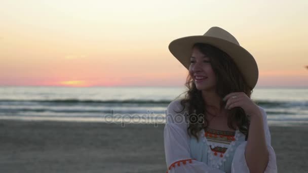 Mujer con sombrero posando en la playa al amanecer — Vídeos de Stock