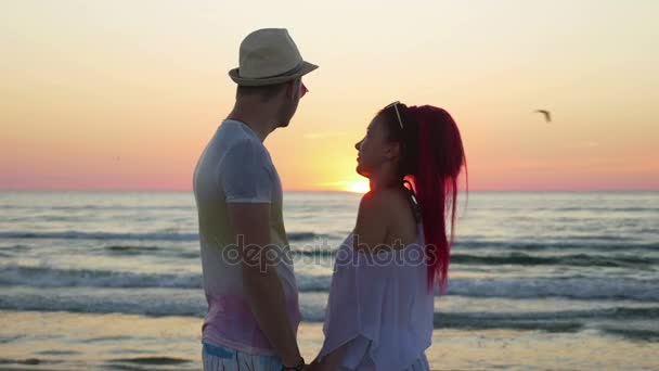 ロマンチックなカップルは手を繋いでいるとサンセット ビーチで水平線を見て — ストック動画