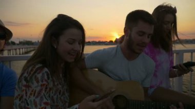 Yavaş çekimde bir köprüde bir gitar ile yaz zamanında şarkı arkadaşlar